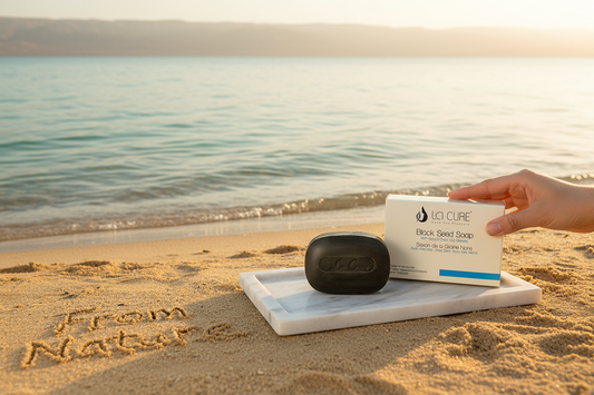 Hand holding a box of LG CURE soap on a beach with 'From Nature' written in sand.